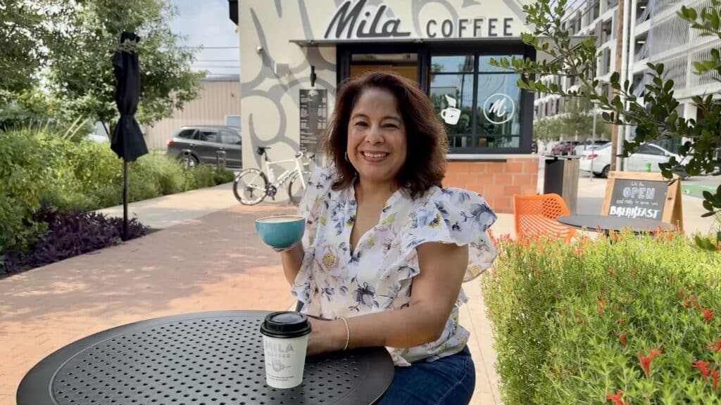 Brenda disfrutando un café en Milla Coffee, cafetería local en San Antonio con ambiente al aire libre en el parque.