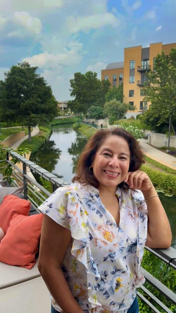Influencer Brenda Cisneros disfrutando en la terraza de Tre Trattoria, restaurante italiano con vista al River Walk en la sección calmada de Museum Reach en San Antonio, Texas, zona cultural y tranquila.